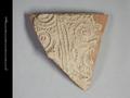 Wall sherd of a clay vessel. The vessel was made using a mould and is decorated with an elaborate foliage pattern. Originally made of deep red clay, it was covered with a cream-coloured slip.