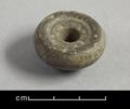 Round loom-weight made of dark brown clay. The base is slightly concave and has an incised ring.