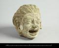 Stucco head of a laughing (?) person. The mouth is wide open, the upper row of teeth clearly visible. The hair is brushed back and falling behind the ears, the face characterised by deep creases. Traces of a white slip and green paint still remain.