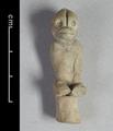 Clay figurine of a sitting monkey. The animal is shown sitting on a small circular object. Both arms and the legs below the thighs are missing.