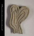 Fragment of a floral ornament made of moulded dark brown clay, possibly depicting a stalk. The object has a wavy shape and increases in width, ending in two rounded lobes.Four deeply incised lines form an additional decoration.