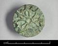Round bronze button with raised settings in the shape of a flower, probably for stone inlays.;