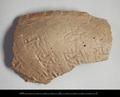 Rim sherd of a hand-made vessel made of coarse red clay with with a light-coloured slip on the outside. The outside has been smoothed and stamped with a rather irregular pattern of bands consisting of L-shapes, crosses and dots.