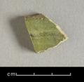 Sherd of a ceramic vessel made of coarse grey clay. One side is still covered with a light green glaze, which has flaked off on the other side.