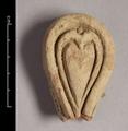 Fragment of wall-decoration made of red clay with a yellow slip. The object is pear-shaped with one oval and one heart-shaped incision. Most likely a lotus-petal is depicted here.