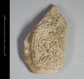 Wall sherd of a clay vessel. The vessel was made using a mould and is decorated with a floral pattern in half relief. It was covered with a white slip before being fired.