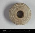 Wooden spindle whorl. The object is disc-shaped and has been decorated with incised concentric circles on one side.