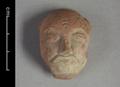 Fragmentary clay figure of a man. Only head and face remain. He is depicted with a bald head, large eyes, a long nose and a thin moustache. The concave shape of the reverse side of the object suggests that it was used as an appliqu for another object, most likely a vessel.;