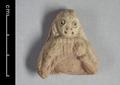 Fragmentary clay figure of a monkey playing a kind of pan pipes, in China known as paixiao (__/__). The animal is shown as having long hair and wearing a bracelet on the left arm. The figure is flat on the reverse side and damaged so that only the upper body remains. It was made using red clay and covered with a light grey slip. The fingerprints of the artists can still be seen on the reverse side.