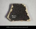 Rimsherd of a ceramic vessel with a black glaze on both sides. The latter is crackled and flaked off in some places.
