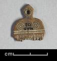 Miniature comb made of bone. It is decorated with grooves and concentric circles. The round top has a projection with a hole drilled into it.