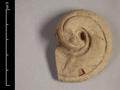 Fragment of a statue, made of red clay with a light-coloured slip. The curled shape, here with two notched lines at the borders, is most commonly addressed as cloud ornament. Often it is part of the border of a halo. The ornament can be curled clockwise or anti-clockwise.