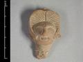 Fragmentary clay figure showing the head of a woman. Her hair is brushed upward from the  forehead and parted in the middle. Her eyes are half-closed and the cheekbones are marked by small incised dots. For an almost identical object see MAS.31.;