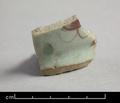 Fragment of a porcelain bowl. This is the base of a vessel with a ringfoot clearly visible. It is glazed with a blueish-grey glaze on both in- and outside. The outside has an additional decoration consisting of red flowers and green dabs which is painted over the glaze.