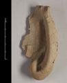 Fragment of a statue made of yellowish brown, fired clay. Elongated human ear with the earlobe missing. The reverse of the fragment is flat and quite rough.