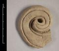 Fragment of an ornament made of yellow clay with traces of a light-coloured slip. The curled shape, here with two notched lines at the borders, is most commonly addressed as cloud ornament. Often it is part of the border of a halo. The ornament can be curled clockwise or anti-clockwise.