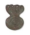 Small ornament made of cast bronze. One part is circular and decorated with concentric circles, the other part is of a semicircular shape and decorated with two smal circles. The lower half of this has four small holes, which were used to fix the object to a surface.;