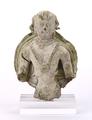 Fragmentary stucco figure of a standing person, possibly a Bodhisattva. The young man has a serene facial expression and a bare upper body which is decorated with beaded necklaces. In the centre of the chest, these are adorned with a rosette. Additionally, he wears flower-shaped earrings and armlets. While the figure was made using a mould, the curls of hair and the jewellery was moulded and applied separately.;