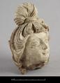 Stucco figure. This is the head of a woman with an elaborate hairstyle. She has a serene facial expression with her eyes half closed and the lips curved into a slight smile.