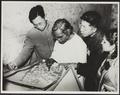 Photograph of Raghu Vira, Chang Shuhong, Sudarshana Devi Singhal and colleague comparing a wall painting copy with the original in the Dunhuang Mogao caves taken in 1955.