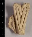 Fragment of a double-lobed leaf-ornament made of yellowish brown clay. Traces of a light-coloured slip.