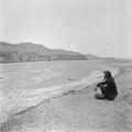 Photograph of Irene Vincent Vongehr on riverbank at Dunhuang Mogao looking across to the northern group of caves in 1948.