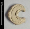 Fragment of wall-decoration made of light grey clay. The crescent-shaped object is decorated with two incised lines.
