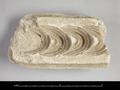 Fragment of a stucco mould used to make a band of crescent-shaped locks of hair.