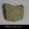 Fragment of a vessel made from coarse red clay. On one side is a very worn green glaze.