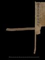 Fragmentary title page of Dunhuang manuscript scroll with stave and remains of silk braid.