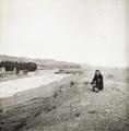 Photograph of a view looking across the river to the Dunhuang Mogao caves with Irene Vincent taken in 1948.