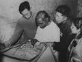 Photograph of Raghu Vira, Chang Shuhong, Sudarshana Devi Singhal and colleague comparing a wall painting copy with the original in the Dunhuang Mogao caves taken in 1955.