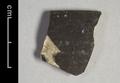 Rim sherd of a vessel covered with a thick dark brown glaze on both sides.