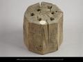 Wooden block. The object has an octagonal shape and six round holes drilled into the upper side. Traces of black paint are visible on the outside. The use of the object is not entirely clear but it could be some sort of incense holder.