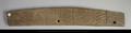 Wooden fragment. The oblong piece of wood is decorated with an incised pattern on one side. The decoration consists of alternating plain and dashed bands as well as two four-petalled flowers set within a circle. Two holes have been drilled into the wood.