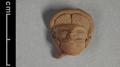 Fragmentary clay figure of a man. Only head and face of the man remain. His hair is brushed upward from the forehead and parted in the middle and he has a moustache. Details such as the strands of hair were rendered using incised lines.